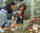 Smiling young mother teaching son how to water plants and flowers in backyard with watering can